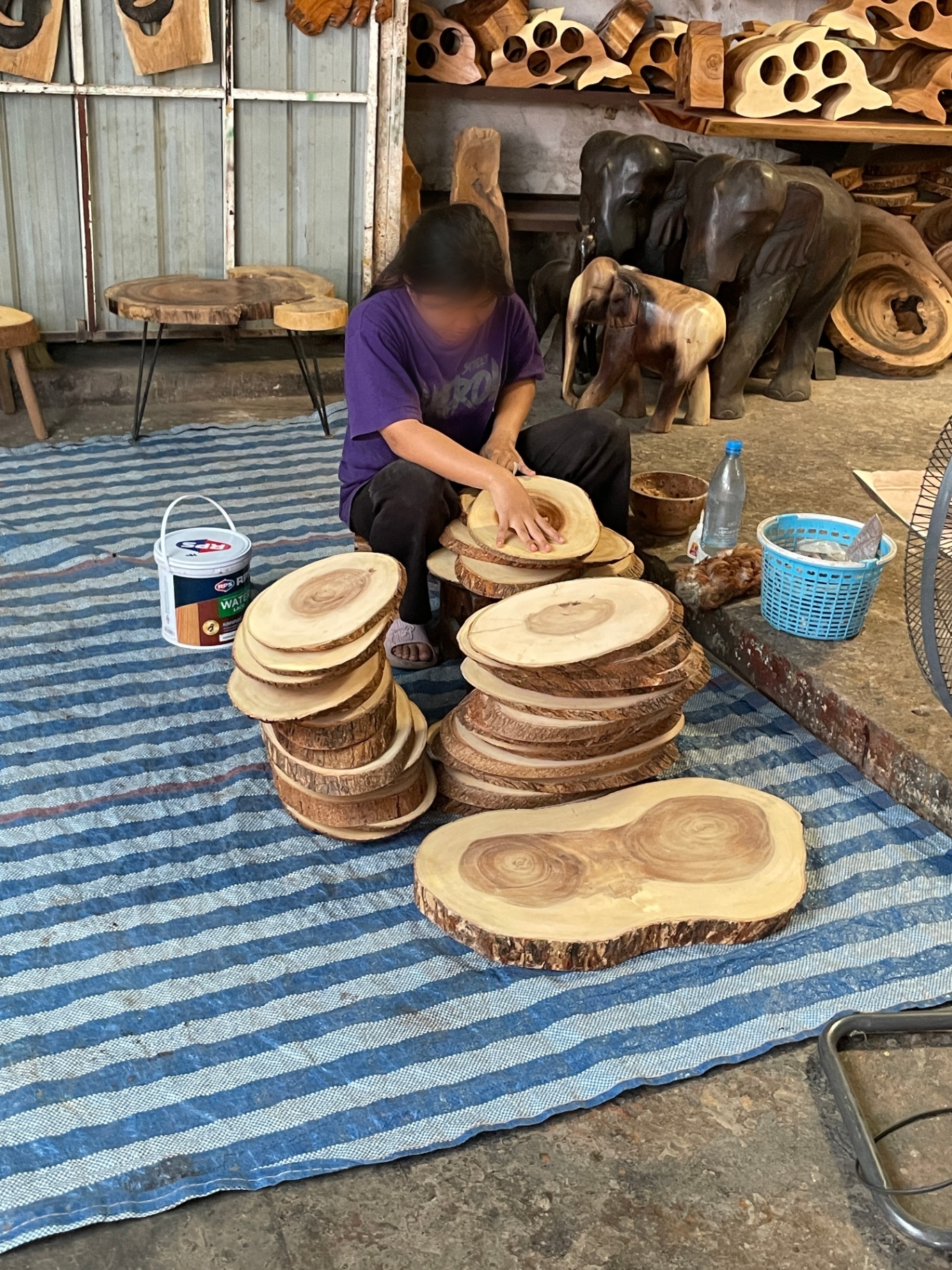 Artisan in northern Thailand hand-finishing wooden slabs